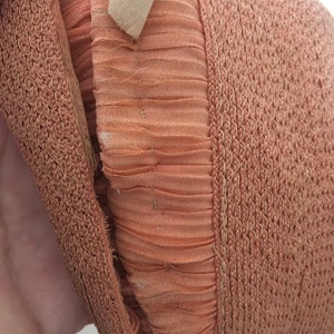 May include: Close-up of a brown woven hat with a brown fabric lining. The hat is folded in half, showing the inside lining.