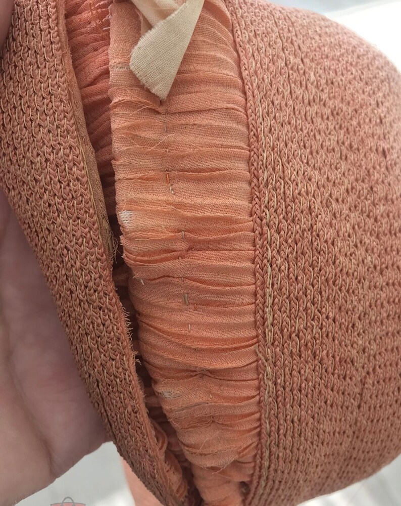 May include: Close-up of a brown woven hat with a brown fabric lining. The hat is folded in half, showing the inside lining.