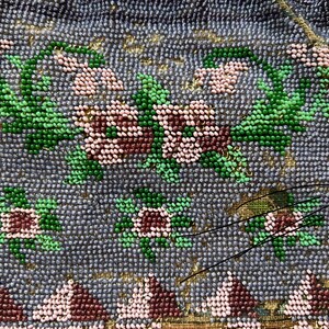 May include: A vintage beaded purse with a floral design. The purse is made of small, colorful beads in shades of pink, green, and brown, sewn onto a light purple fabric. The purse has a clasp closure and a beaded fringe.