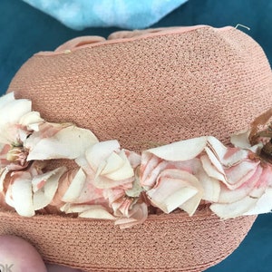 May include: A pink straw hat with a white and pink flower trim.
