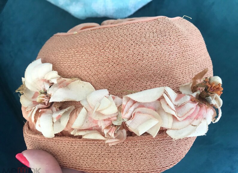 May include: A pink straw hat with a white and pink flower trim.