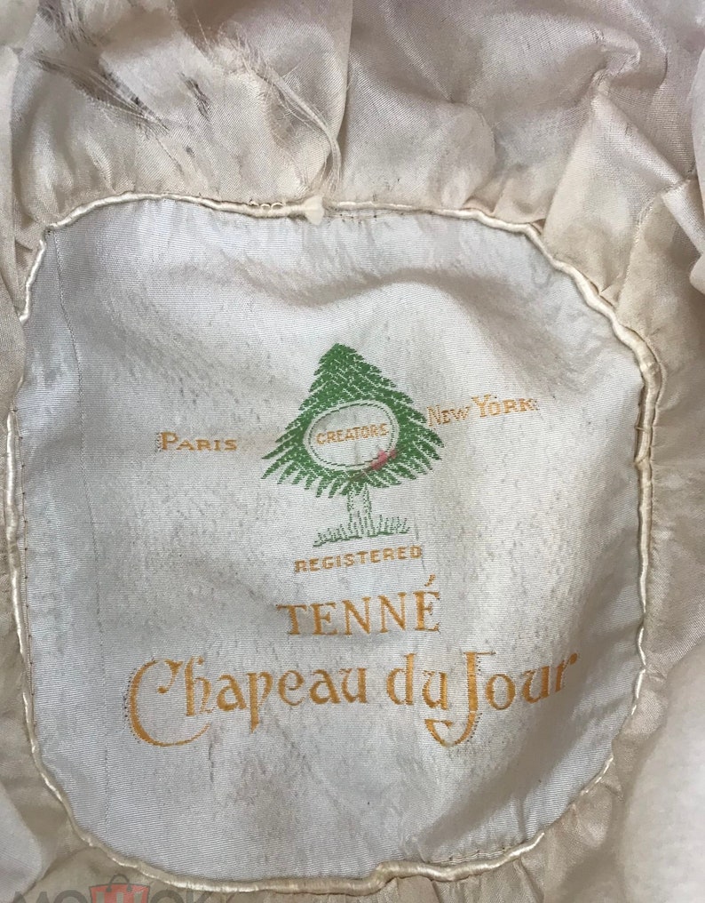 May include: A white hat with a green pine tree logo and the text "Paris Creators New York Registered TENN&Eacute; Chapeau du Jour".
