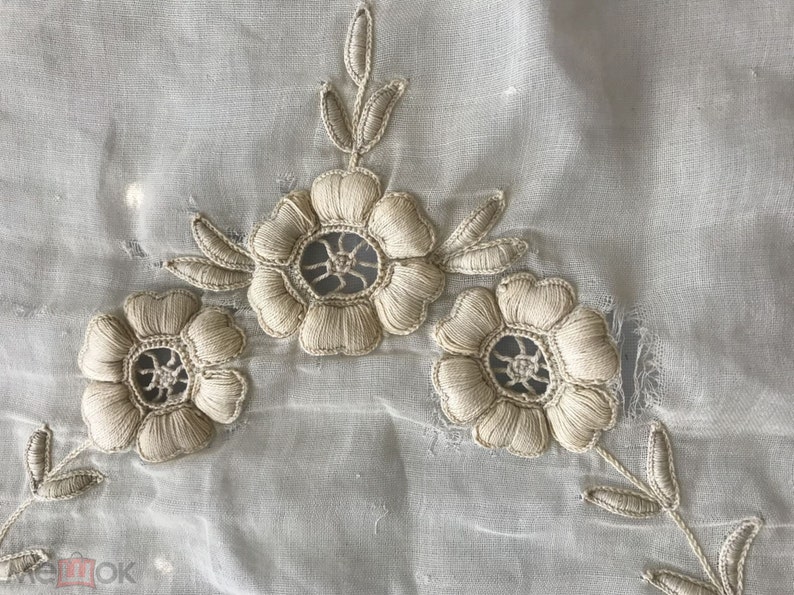 May include: White sheer fabric with delicate embroidered flowers. The flowers are beige and have a lacy design.