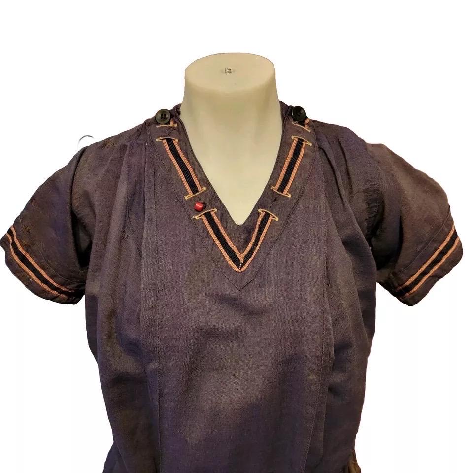 This Edwardian era bathing suit from the early 1900s features a navy color with gold nautical trim. It has attached pantaloons and is made o