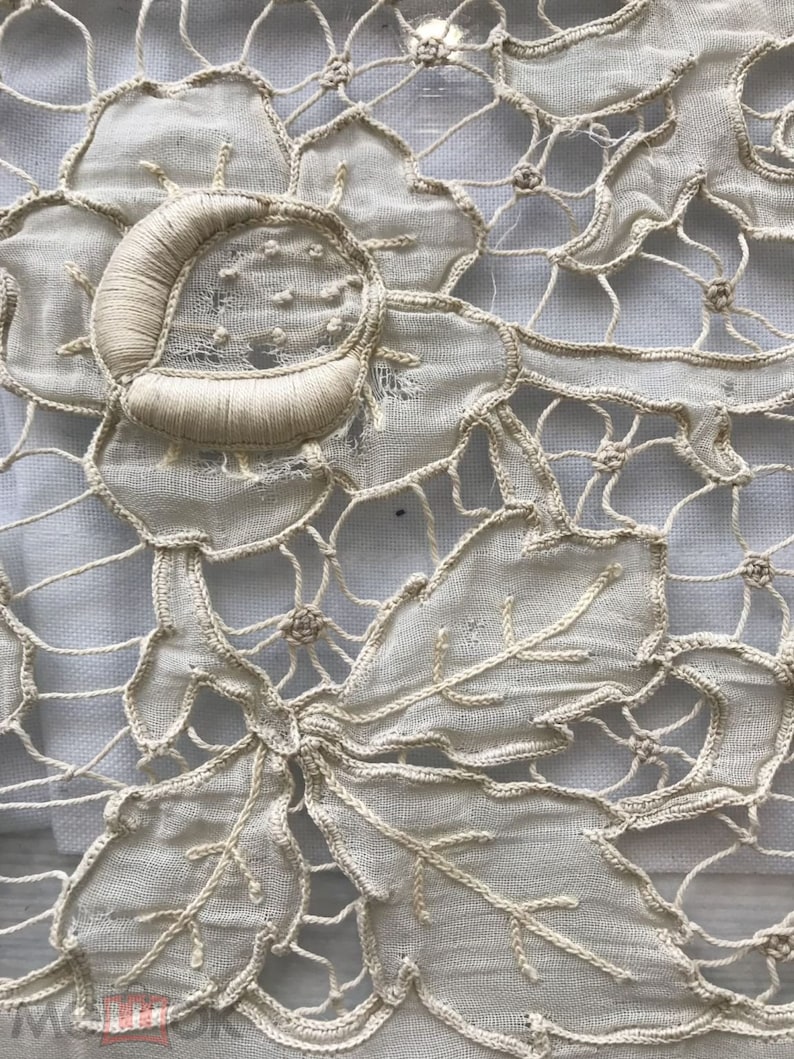 May include: Close-up of a delicate white lace fabric with a floral design. The lace features intricate stitching and a delicate, airy texture.