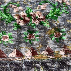 May include: Close-up of a beaded purse with a floral design. The purse is made of small, iridescent beads in shades of blue, green, pink, and brown. The floral design is intricate and detailed, with leaves and flowers.