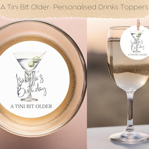 May include: A white round drink topper with a martini glass and olives, with the text "Isabella's Birthday A Tini Bit Older".