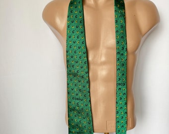 May include: A green silk tie with a repeating pattern of black horseshoes and yellow stars. The tie has the text "D&G" printed on it.