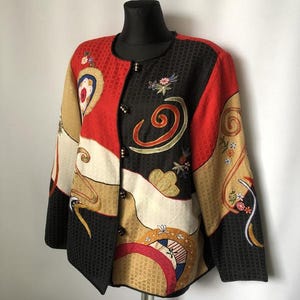Könnte beinhalten: Eine farbenfrohe, gemusterte Jacke mit einem einzigartigen Design. Die Jacke hat eine Mischung aus roten, schwarzen, goldenen und cremefarbenen Farben mit floralen und abstrakten Mustern. Sie hat einen runden Kragen und wird mit schwarzen Knöpfen geschlossen.