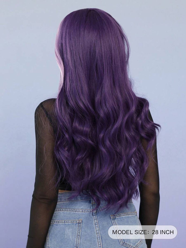 May include: A long, wavy purple wig, approximately 28 inches in length, is shown from the back. The wig has a deep purple hue with a slight pinkish undertone. The model is wearing a black mesh top and blue jeans.