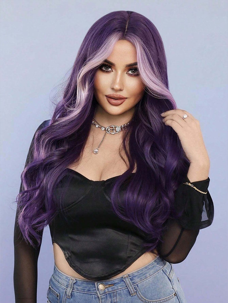 May include: A woman with long, wavy purple hair with a light purple highlight. She is wearing a black top, a silver necklace, and blue jeans. The background is a light blue.