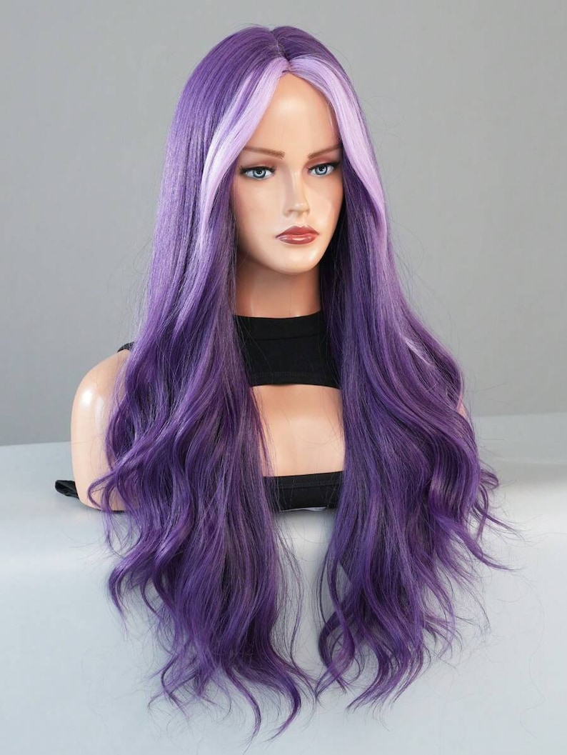 May include: A long, wavy wig in shades of purple and lavender is displayed on a mannequin head. The wig features a dark purple base with lighter lavender highlights framing the face. The hair is styled with loose waves, creating a voluminous and natural look.