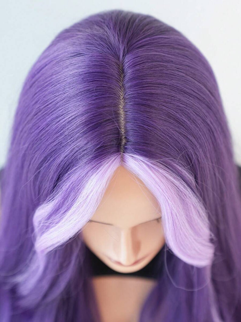 May include: A purple wig with a light purple front section. The wig is styled with long, straight hair and a natural-looking part. The wig is on a mannequin head.