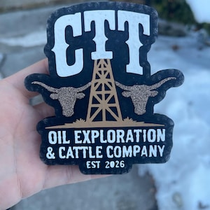 Pode incluir: Um autocolante preto e branco da CTT Oil Exploration & Cattle Company com um design de plataforma petrolífera e longhorn dourado. O autocolante inclui o texto "EST 2026".