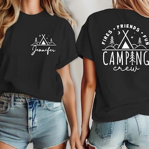 Könnte beinhalten: Zwei schwarze T-Shirts mit weißem Text und Grafiken. Ein Shirt sagt "Fires Friends Fun Camping Crew" mit einem Lagerfeuer und Bäumen. Das andere Shirt sagt "Jennifer" mit einem Lagerfeuer und Bäumen.
