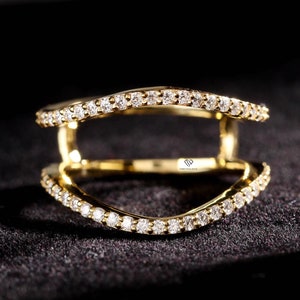 May include: A gold ring with two bands, each set with a row of small diamonds. The bands are curved and intersect in the center.