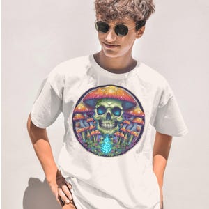 May include: White t-shirt with a colorful graphic of a skull surrounded by mushrooms. The skull has blue eyes and a green nose. The mushrooms are red, orange, yellow, and green.