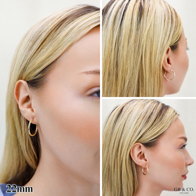 May include: A pair of gold hoop earrings with a smooth, polished finish. The earrings are circular in shape and feature a thin, lightweight design. The text 22mm is visible in the bottom left corner, and the text GB & CO. NEW YORK is in the bottom right.