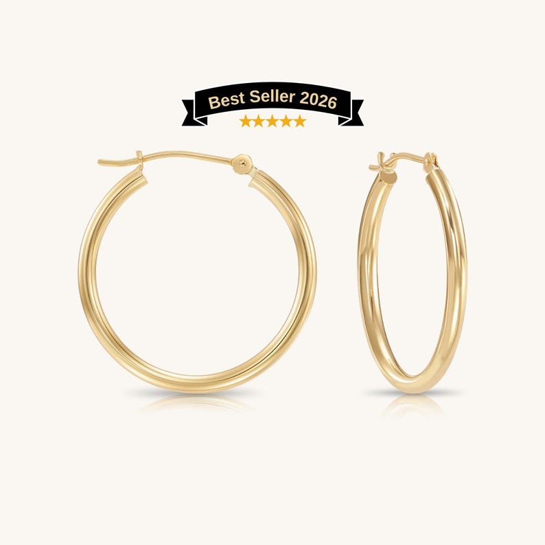 A pair of polished gold hoop earrings with a smooth, rounded profile and a secure hinged clasp mechanism. Made 10k or 14K gold with 2mm thickness and perfect for everyday. Solid gold hoops for women and girl