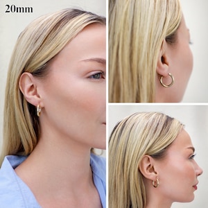 May include: A pair of gold-toned hoop earrings with a smooth, polished finish. The earrings have a circular design and a diameter of 20mm. The hoops are shown from multiple angles, highlighting their simple, rounded profile and secure closure.