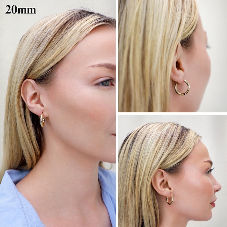 May include: A pair of gold-toned hoop earrings with a smooth, polished finish. The earrings have a circular design and a diameter of 20mm. The hoops are shown from multiple angles, highlighting their simple, rounded profile and secure closure.