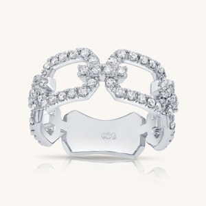 May include: A white gold ring with a double infinity symbol design, set with small diamonds.