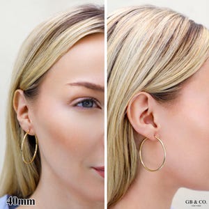May include: A pair of gold hoop earrings with a smooth, circular design. The earrings have a diameter of 40mm as indicated by the text in the corner. The brand name GB & CO. NEW YORK is printed in the bottom right corner of the image.
