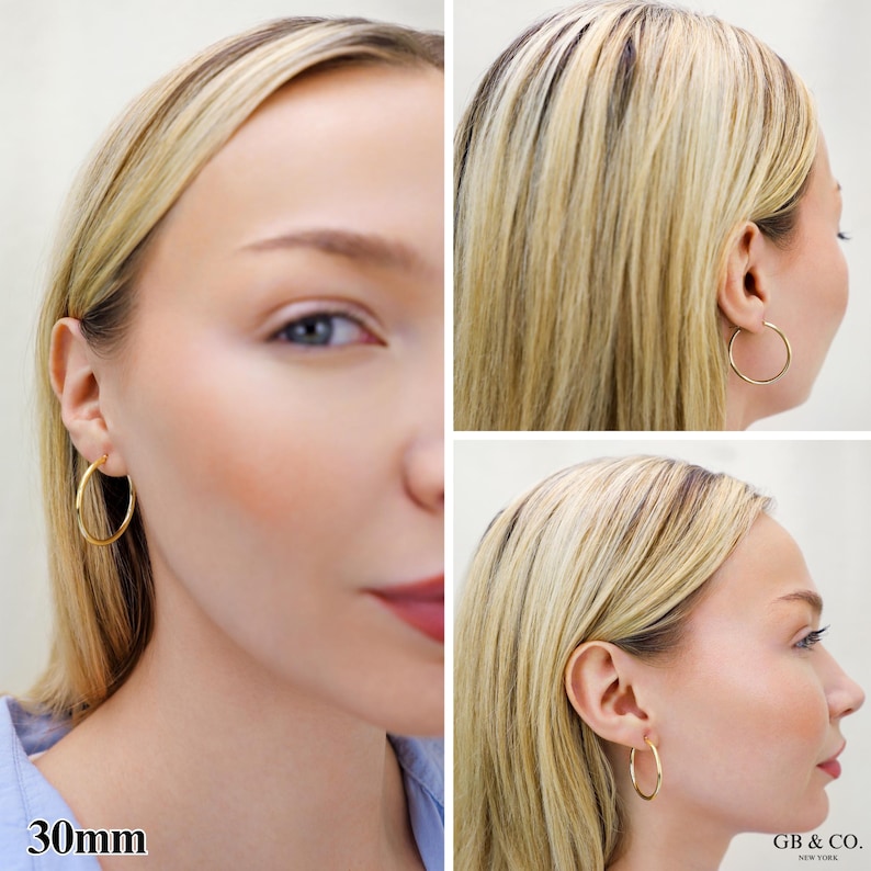May include: A pair of gold hoop earrings with a 30mm diameter. The earrings are circular, thin, and polished, featuring a simple wire closure. The text 30mm is visible in the bottom left corner, and the brand name GB & CO. NEW YORK is in the bottom right.