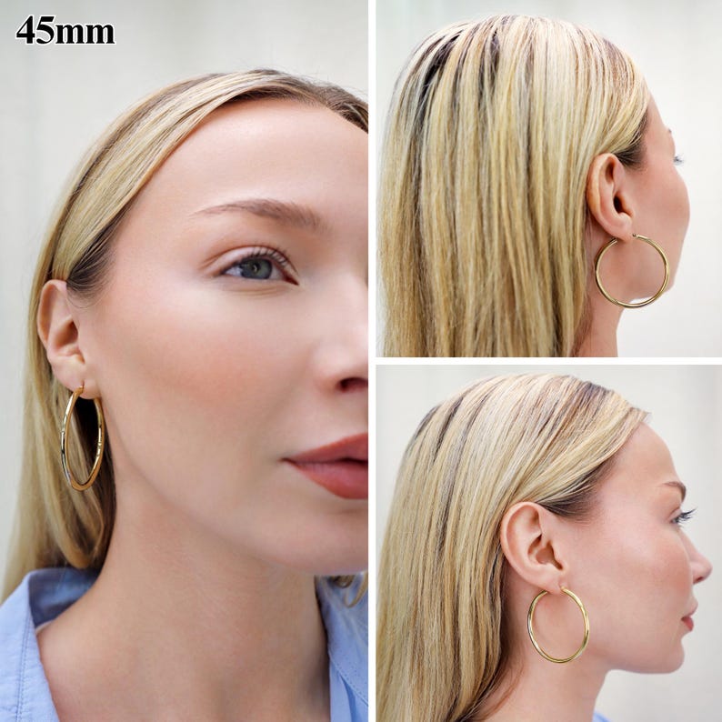 May include: A pair of gold-toned hoop earrings with a smooth, polished finish. The circular earrings have a diameter of 45mm. The hoops are shown from multiple angles, highlighting their simple, round, and continuous design worn in the earlobes.