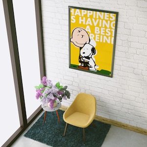 Può includere: Un poster con cornice gialla con un'immagine di cartone animato di Snoopy e Charlie Brown che si abbracciano. Il poster ha il testo "Happiness is having a best friend" su uno sfondo giallo.
