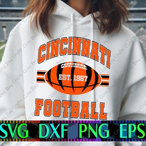 May include: White hoodie with the words "CINCINNATI FOOTBALL" in orange and black. A football graphic with "EST. 1967" is centered. The bottom of the image shows "SVG DXF PNG EPS" in green, blue, and black.