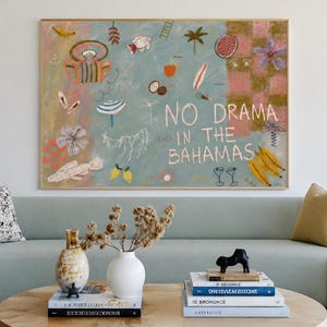 Könnte beinhalten: Ein rechteckiges Wandbild mit hellblauem Hintergrund, verschiedenen bunten Illustrationen tropischer Motive und dem weißen Schriftzug "NO DRAMA IN THE BAHAMAS". Das Kunstwerk ist in einem hellen Holzrahmen gefasst und hängt über einem Sofa.