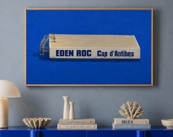 May include: A rectangular framed wall art print featuring a beige swimming pool diving board against a solid blue background with the text EDEN ROC Cap d'Antibes in blue lettering, displayed above a glossy blue sideboard with rounded edges.