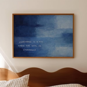 May include: A rectangular wall art print in a wooden frame featuring a deep blue watercolor-style background with white text that reads: EVERYTHING IS A WIN WHEN THE GOAL IS EXPERIENCE. The artwork is displayed horizontally on a plain wall.