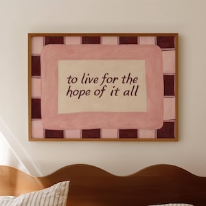 Könnte beinhalten: Ein gerahmtes Kunstwerk mit dem Text "to live for the hope of it all". Das Kunstwerk zeigt einen rosa-braunen karierten Rand mit einem rosa Innenrechteck. Der Rahmen ist aus Holz.