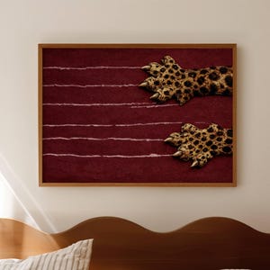 May include: A rectangular wall art print in a wooden frame featuring a deep maroon background with horizontal white scratch marks and two leopard paws with visible claws appearing to emerge from the right side of the textured surface.
