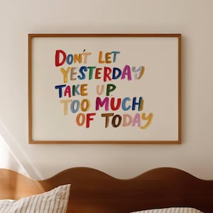 Könnte beinhalten: Ein rechteckiger Wandkunstdruck in einem dünnen Holzrahmen mit dem mehrfarbigen, handgeschriebenen Text: Don't let yesterday take up too much of today. Die Buchstaben sind in verschiedenen leuchtenden Farben wie Rot, Gelb, Blau und Pink gemalt.
