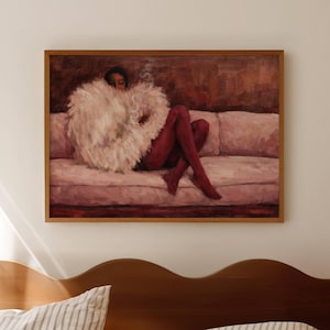 Może przedstawiać: Oprawiony obraz przedstawia osobę leżącą na różowej sofie, ubraną w białą, pierzastą odzież i czerwone rajstopy. Dzieło ma ciepłą paletę barw z brązowymi i różowymi tonami. Obraz jest wyświetlany nad drewnianą ramą łóżka.