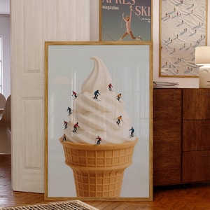 May include: A framed art print depicting skiers on a soft-serve ice cream cone. The cone is light brown, and the ice cream is white. Two other framed prints are visible, one with the text "APRES SKI".