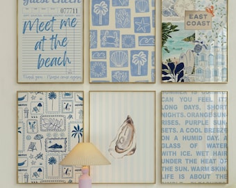 May include: A gallery wall featuring six framed prints with coastal themes in blue and white, including a guest check design, a shell pattern, an East Coast collage, a stamp motif, an oyster illustration, and a blue text print about summer.