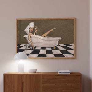 May include: A framed wall art print depicting a person with a white towel wrapped around their head, relaxing in a white clawfoot bathtub. The person holds a glass of champagne and a magazine with the word VOGUE visible, set against a checkered floor.