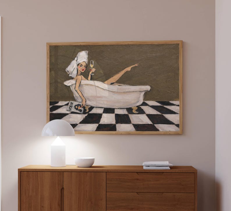 May include: A framed wall art print depicting a person with a white towel wrapped around their head, relaxing in a white clawfoot bathtub. The person holds a glass of champagne and a magazine with the word VOGUE visible, set against a checkered floor.