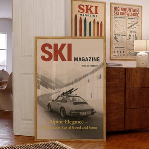 Pode incluir: Três cartazes vintage emoldurados da "SKI MAGAZINE" com molduras de madeira são exibidos. O cartaz central apresenta um carro a conduzir numa estrada com neve. Os outros cartazes têm gráficos e texto relacionados com o esqui. A sala tem um chão de madeira e uma porta branca.