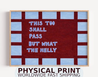 May include: A rectangular wall art print in a light wood frame featuring a dark maroon central field with a grid of light blue squares around the border. The text in light blue reads: THIS TOO SHALL PASS BUT WHAT THE HELLY.