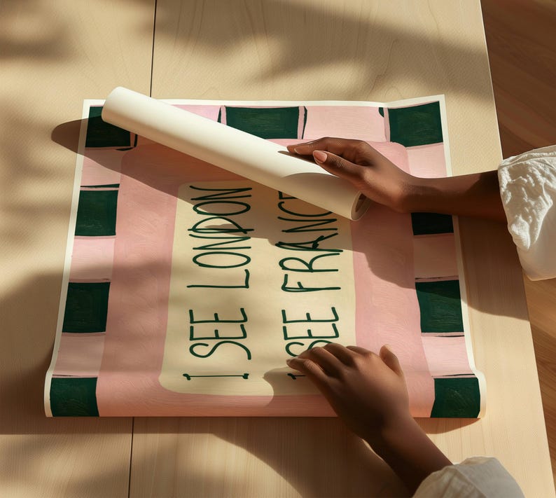 Puede incluir: Un p&oacute;ster rectangular con fondo rosa claro y un borde a cuadros verde oscuro. El centro contiene un rect&aacute;ngulo de color crema con el texto en verde oscuro I SEE LONDON I SEE FRANCE escrito en una fuente de estilo manuscrito.