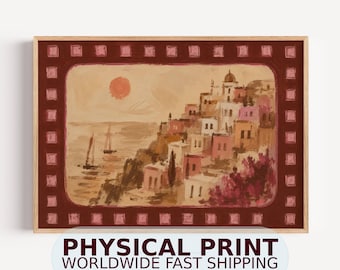 May include: A rectangular wall art print featuring a coastal village scene with white and pink buildings, a calm sea with two sailboats, and a round orange sun. The artwork is framed by a dark red border with a repeating pattern of pink squares.