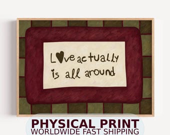 May include: A framed wall art print featuring a dark red rectangular center with a cream-colored rectangle in the middle. The text "Love actually is all around" is written in dark brown, with a heart replacing the letter "o" in "Love".