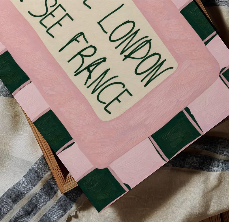 Puede incluir: Una impresi&oacute;n art&iacute;stica rectangular con un fondo rosa claro y acentos rectangulares de color verde oscuro en los bordes. El centro contiene un panel color crema con el texto verde oscuro "SEE LONDON SEE FRANCE" en estilo manuscrito.