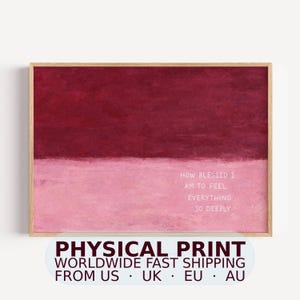 May include: A rectangular wall art print in a light wood frame featuring a horizontal split composition. The top half is a deep burgundy red, and the bottom half is a soft light pink. The text reads: HOW BLESSED I AM TO FEEL EVERYTHING SO DEEPLY.