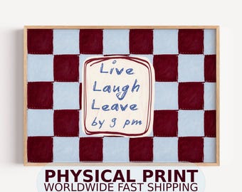 May include: A rectangular wall art print in a light wooden frame featuring a checkered pattern of dark maroon and light blue squares. In the center, a cream-colored square contains the handwritten blue text: Live Laugh Leave by 9 pm.